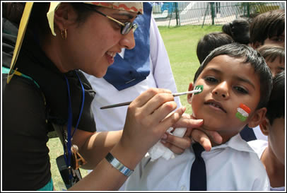 A boy gets his face painted with the Indian and Pakistani flags.