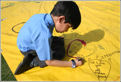 A Pakistani boy signs The World's Largest Love Letter, writing "WE LOVE YOU INDIA" inside a big red heart. 