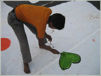 A boy paints a green heart on the gigantic letter.