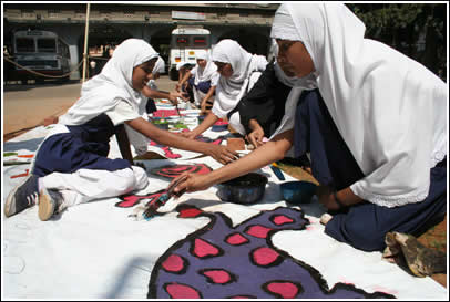 Students at Allana High School help paint the border tarps.